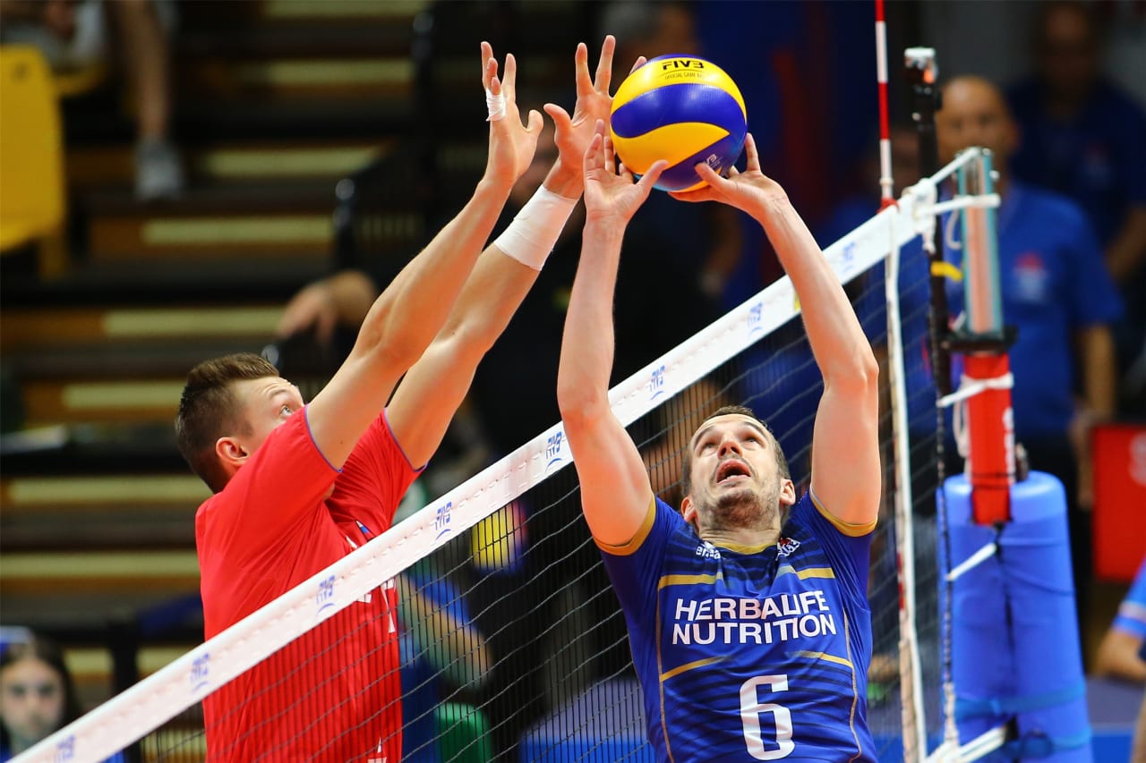 Benjamin Toniutti sets the ball while Dmitriy Volkov tries to block